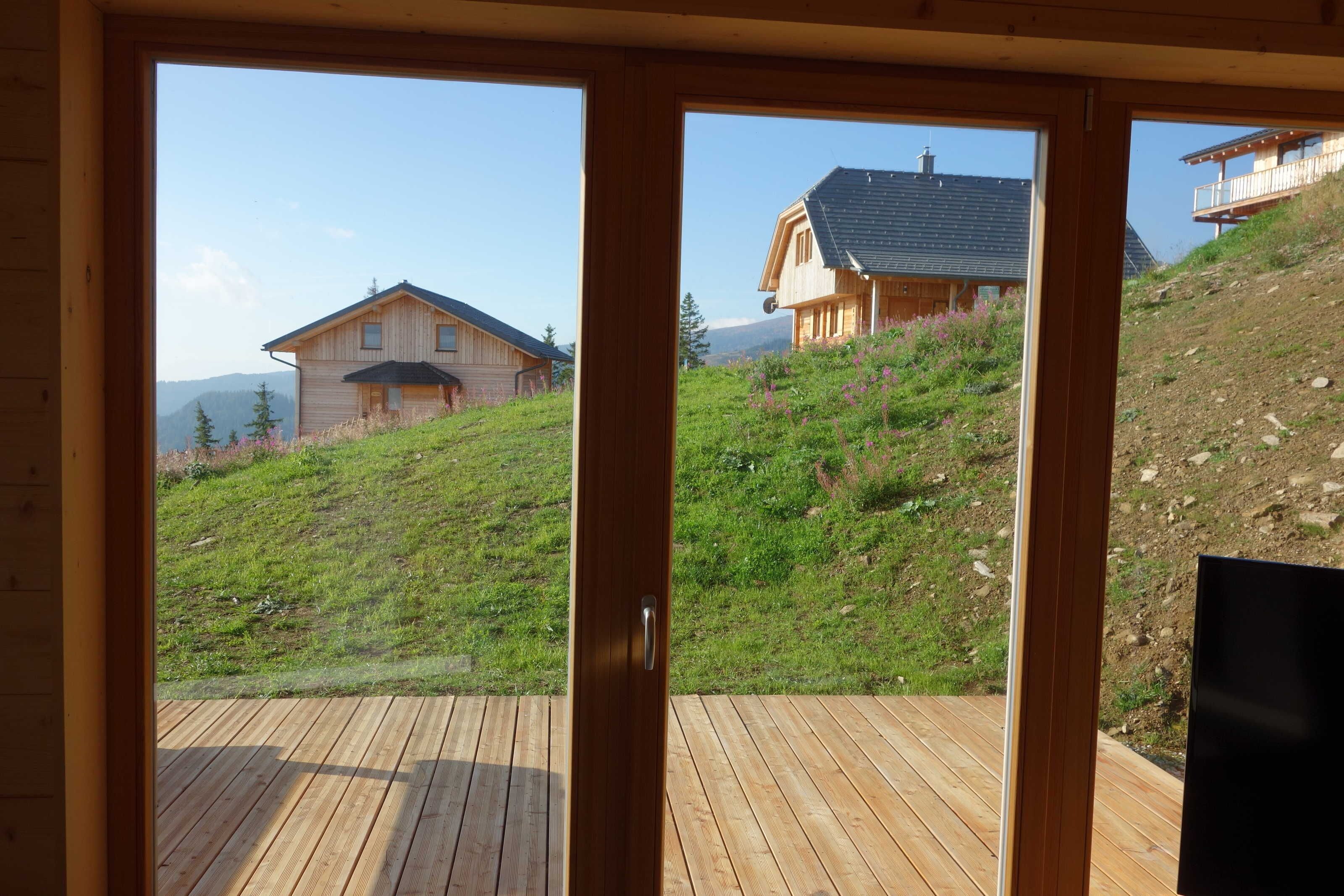 Een houten terras met uitzicht op een heuvel en twee huizen.
