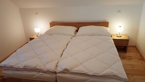 A double bed with a quilted duvet, two bedside tables with lamps, and a wooden headboard.
