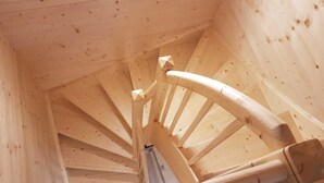 Un escalier en colimaçon en bois, doté d’une main courante et d’un mur en bois.