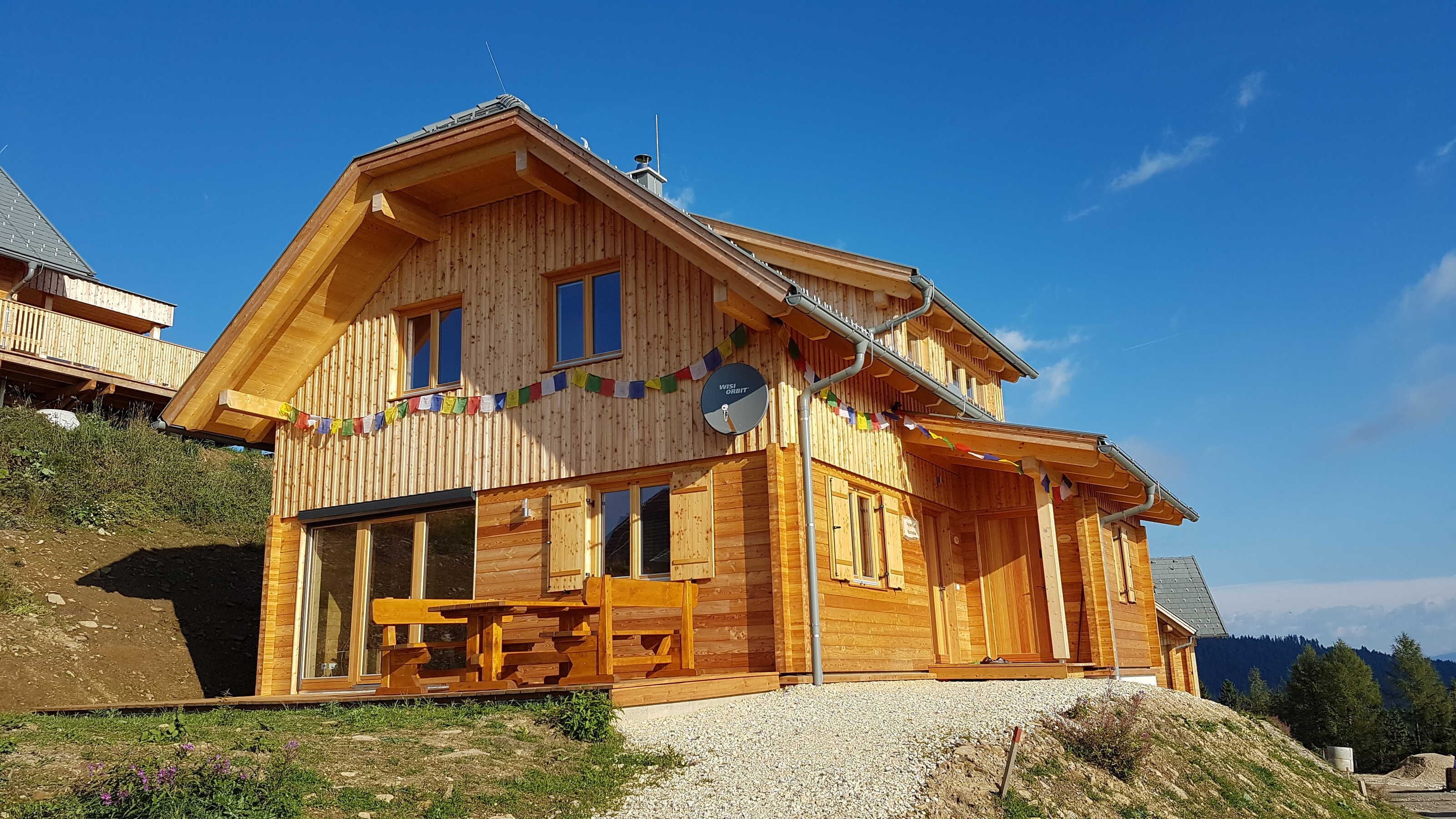 Eine Holzhütte mit Balkon, großen Fenstern und einer Sat-Anlage.