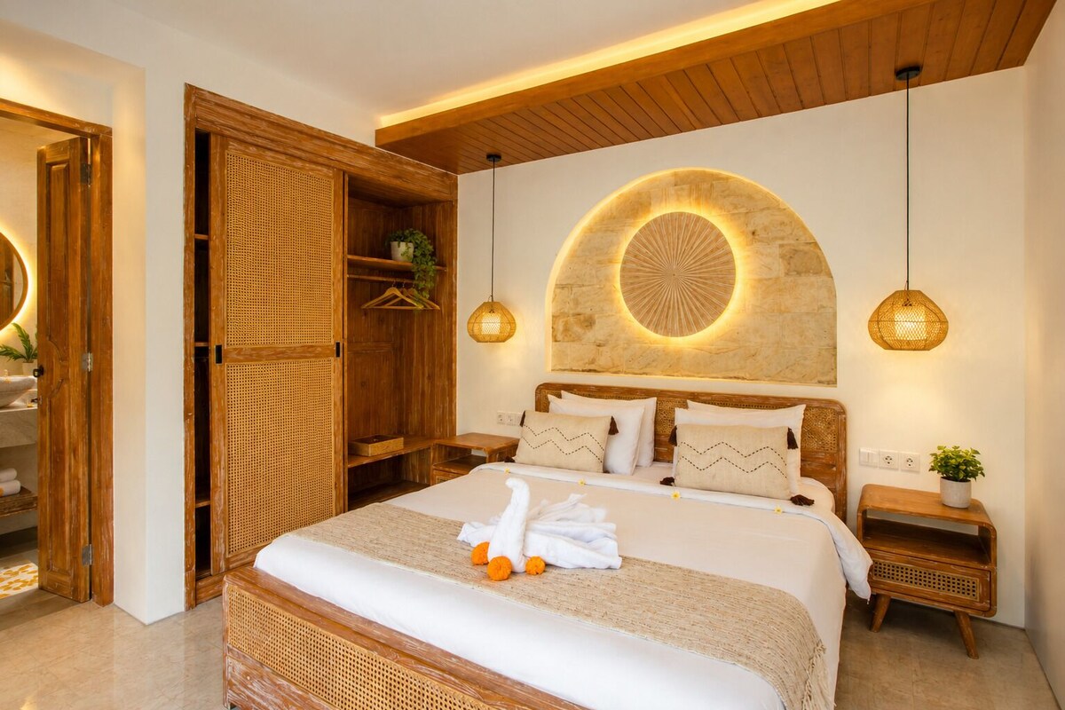 Une chambre avec un grand lit, une armoire en bois et un luminaire circulaire fixé au mur.