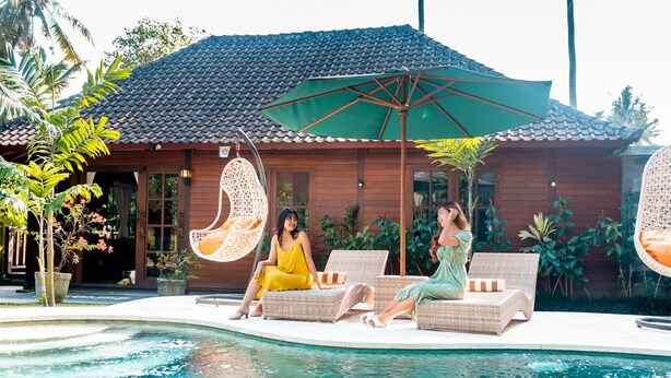 Ein Poolbereich mit Korlounge-Stühlen, einer Hängematte und einem großen Sonnenschirm.