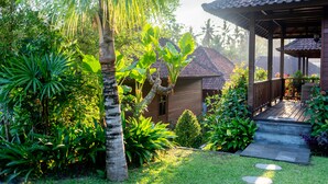 A wooden structure with a tiled roof, surrounded by lush greenery and a well-maintained garden. - Villa Waturenggong Ubud (Ubud)