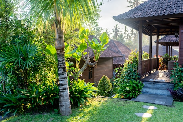 Une structure en bois surmontée d’un toit en tuiles, entourée d’une végétation luxuriante et d’un jardin bien entretenu.