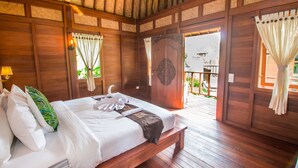 A wooden room with a bed, curtains, and a view of the outside. - Villa Waturenggong Ubud (Ubud)