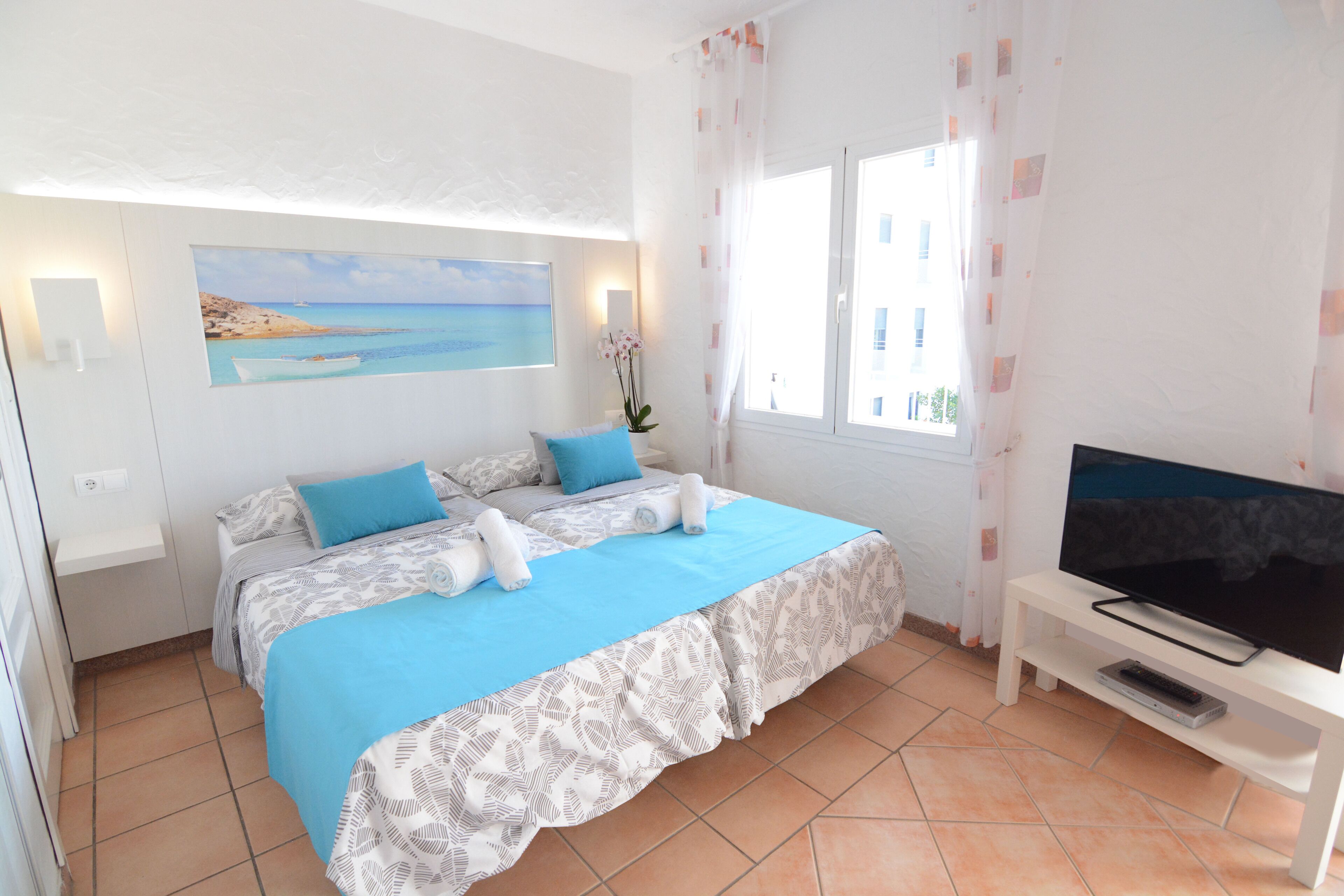 A bedroom with a bed, a TV, and a painting on the wall.