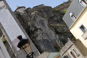 A stone building with a steep, rocky cliff in the background. - Castel de Mirambel (Lourdes)