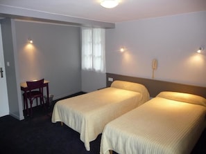 A hotel room with two single beds, a desk, and a chair. - Castel de Mirambel (Lourdes)