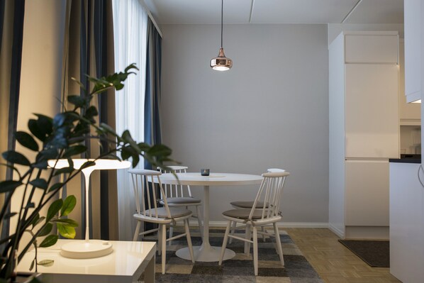 A modern dining area with a round table and four chairs, a pendant light, and a potted plant. - Hotel Epoque (Jakobstad)