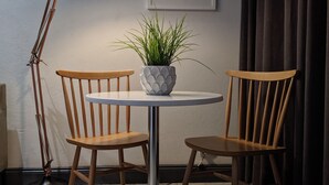A room with a round table, two wooden chairs, a floor lamp, a potted plant, and a framed artwork on the wall. - Junction 502 Apartments (Pretoria)