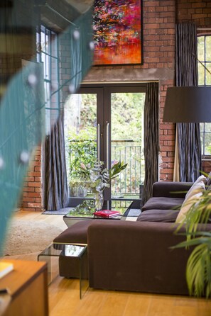 Un salon moderne avec un canapé marron, une table basse en verre et une plante en pot.