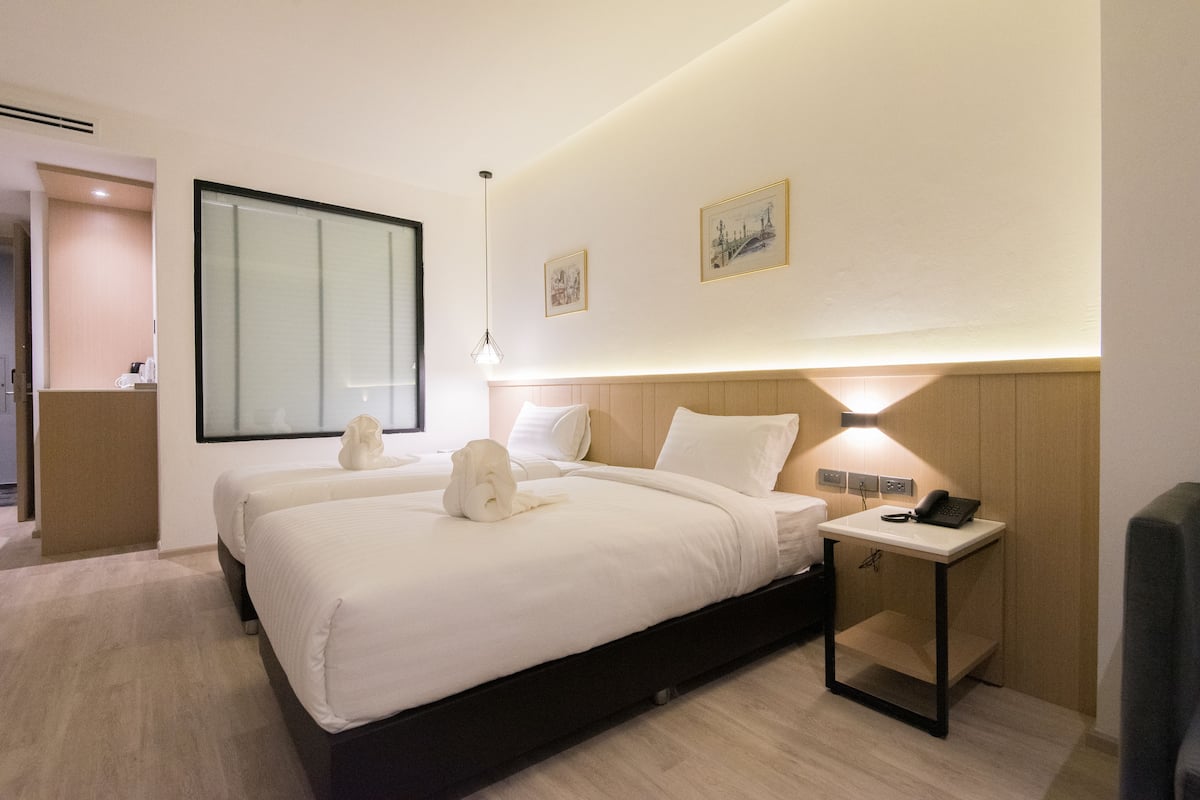 Una habitación de hotel con una cama grande, mesitas de noche, un escritorio con lámpara y obras de arte en las paredes.
