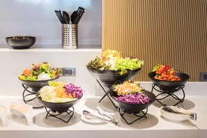 A buffet with various salads and bowls of food on a white countertop. - Madison Bangkok (Bangkok)
