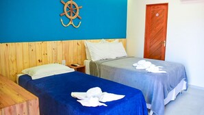 Habitación de hotel con dos camas, cabecero de madera, un adorno de ancla en la pared y una puerta con letrero de prohibido fumar.
