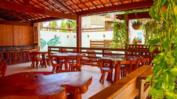 Un restaurant avec des tables et des chaises en bois, un mur recouvert de carreaux et une vue sur la rue.