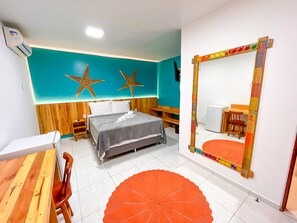 Habitación de hotel con cama, escritorio, silla, espejo y un adorno con forma de estrella en la pared.