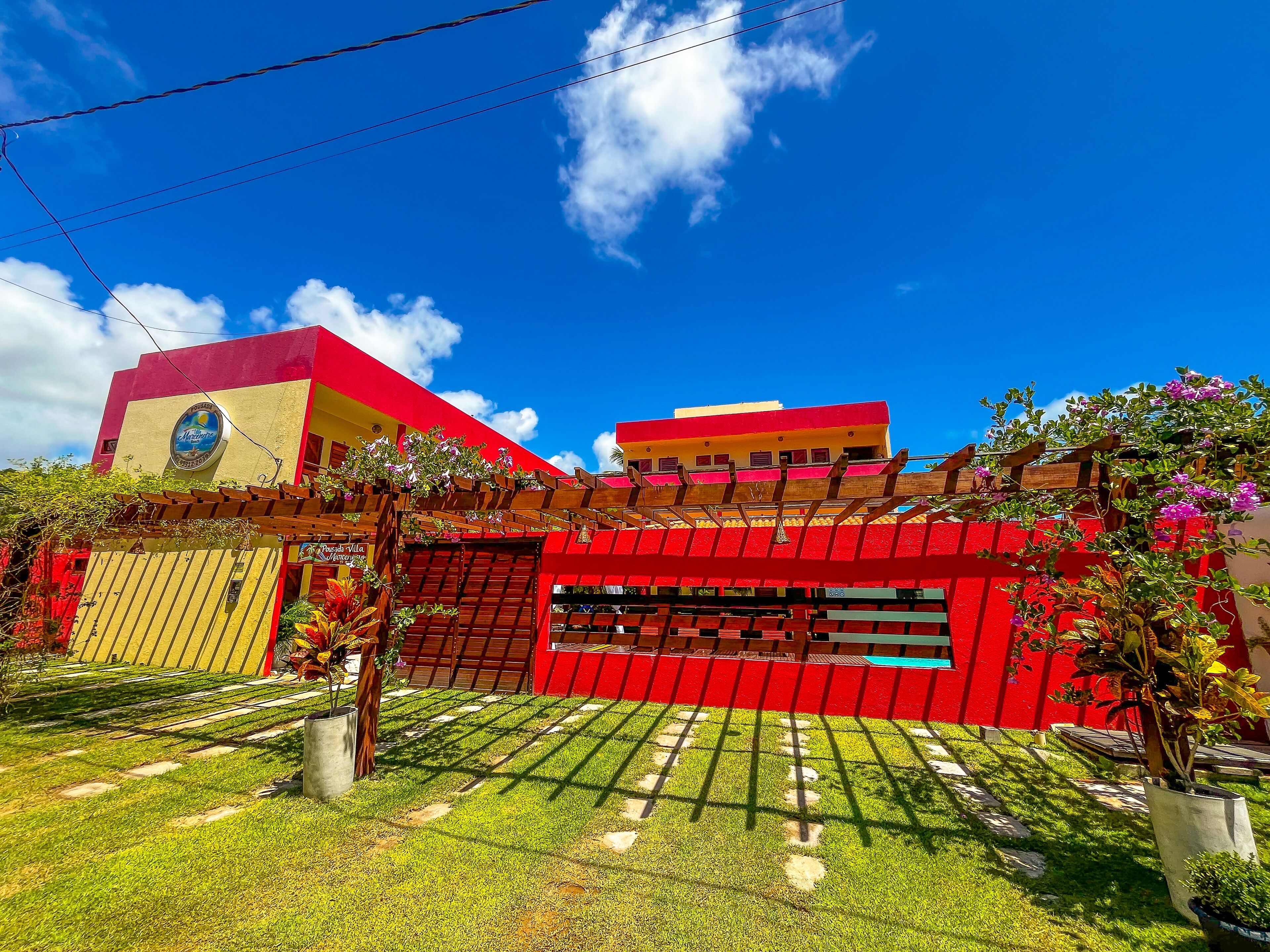 A building with a red facade, a visible sign for "Pura Villa," and a clear blue sky.
