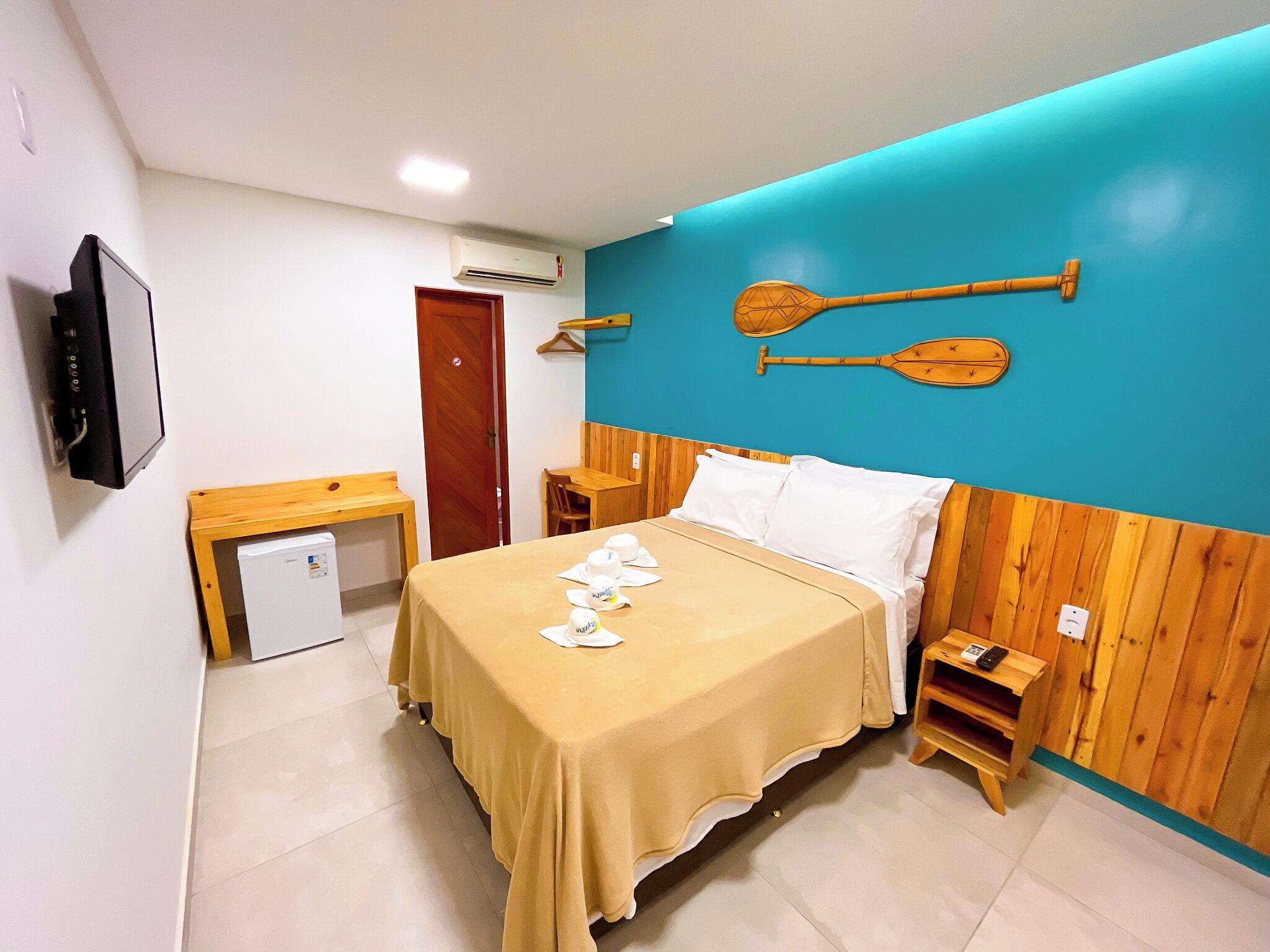 A hotel room with a bed, a desk, a TV, and a small fridge.