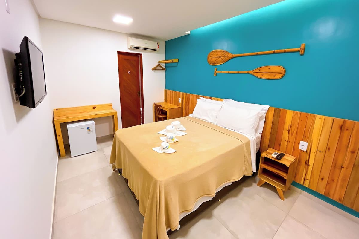 A hotel room with a bed, a desk, a TV, and a small fridge.