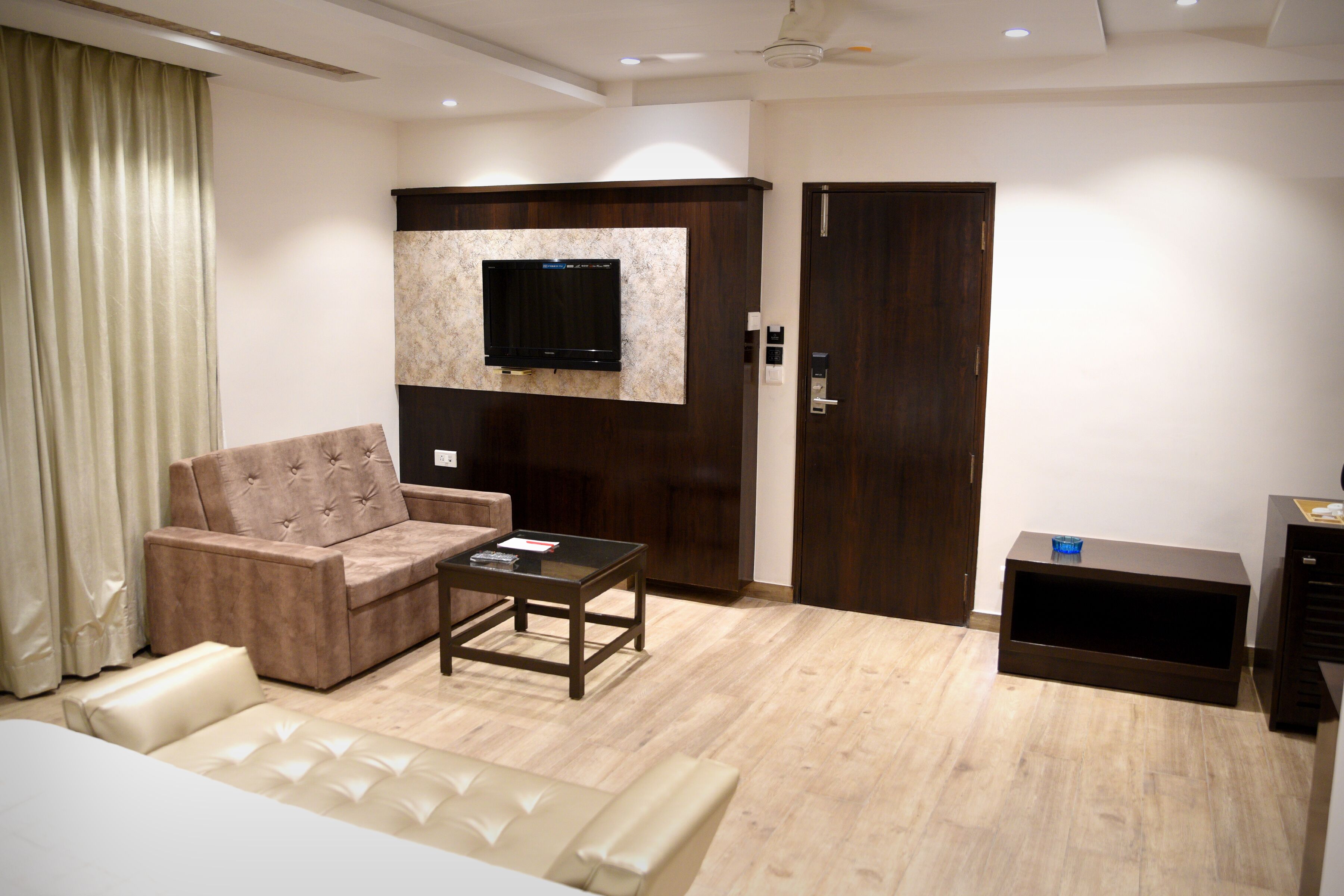 Una sala moderna con un sofá, una mesa de centro, un televisor de pantalla plana montado en un panel de madera, un armario y un mueble auxiliar.