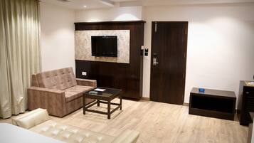 Una sala moderna con un sofá, una mesa de centro, un televisor de pantalla plana montado en un panel de madera, un armario y un mueble auxiliar.