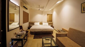 Habitación de hotel con una cama grande, un sofá, una mesita, un espejo y un ventilador de techo.