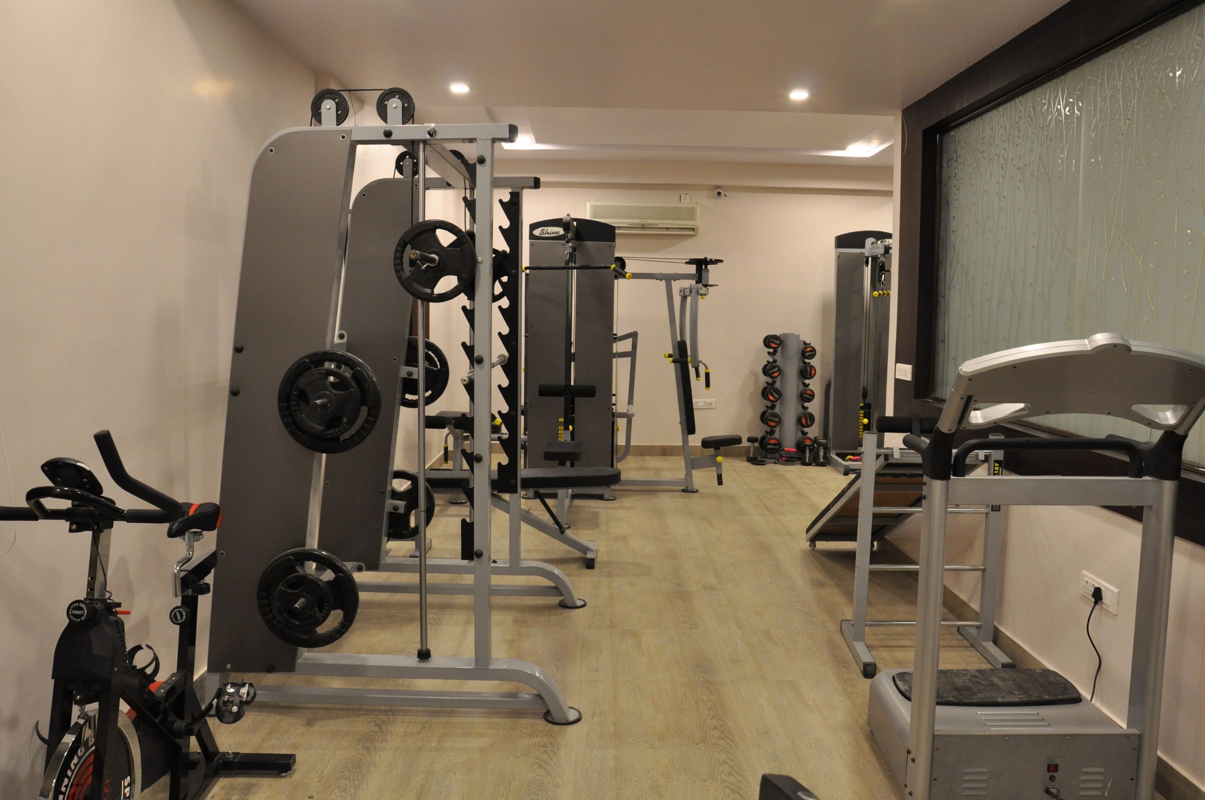 A gym with various exercise equipment including a treadmill, weight machines, and a stationary bike.