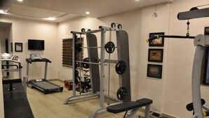 Un gimnasio con máquinas de cardio, equipo de levantamiento de pesas y una cinta de correr.