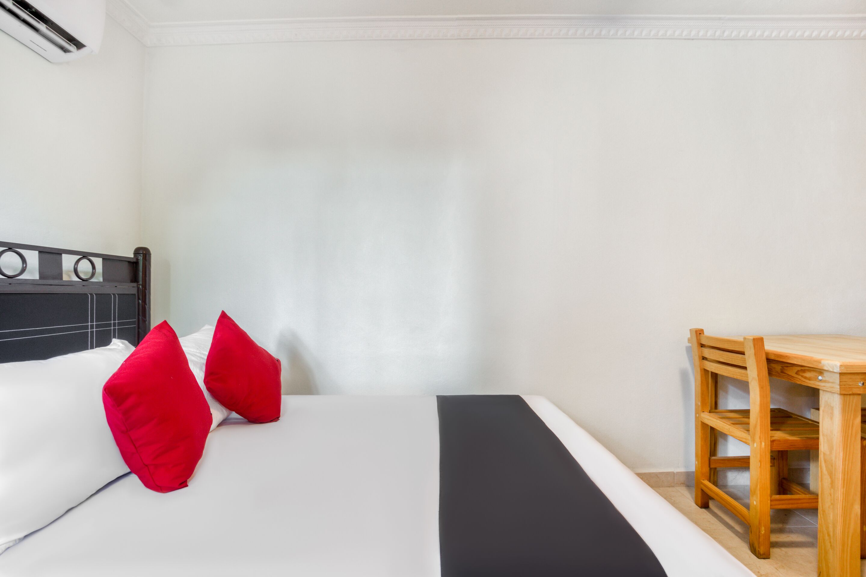 A room with a bed, a wooden chair, and a small table.