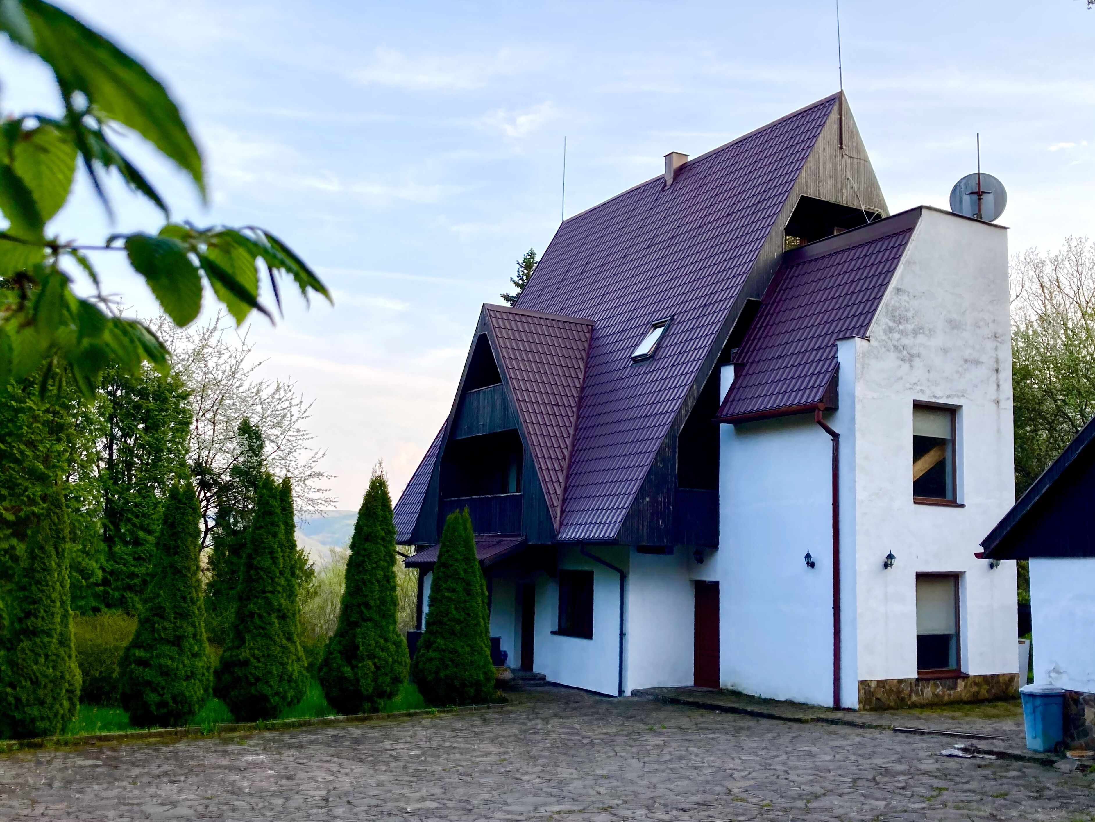 Een huis met een schuin dak, schoorsteen en een schotelantenne.