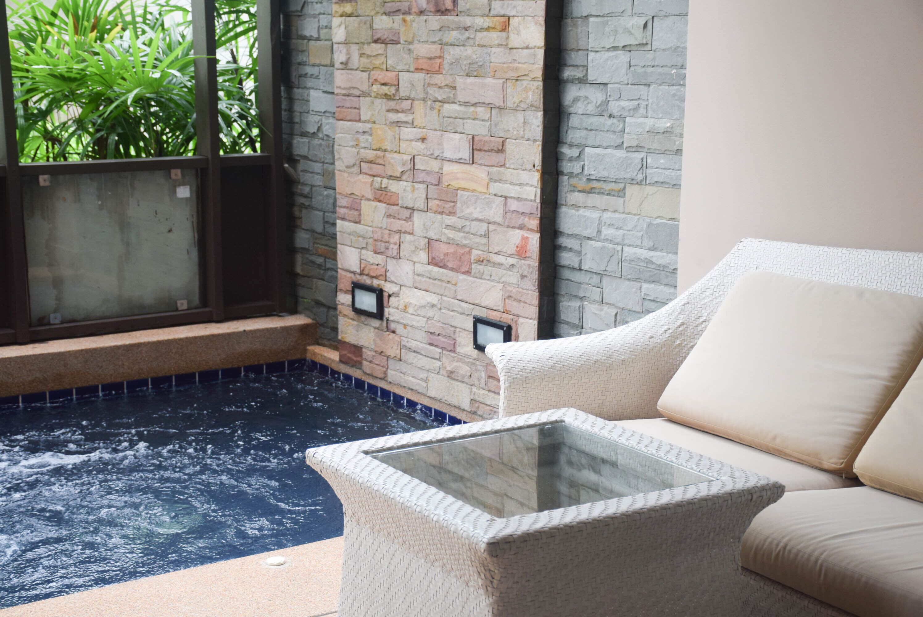 A spa area with a stone wall, a glass-topped table, and a beige sofa.