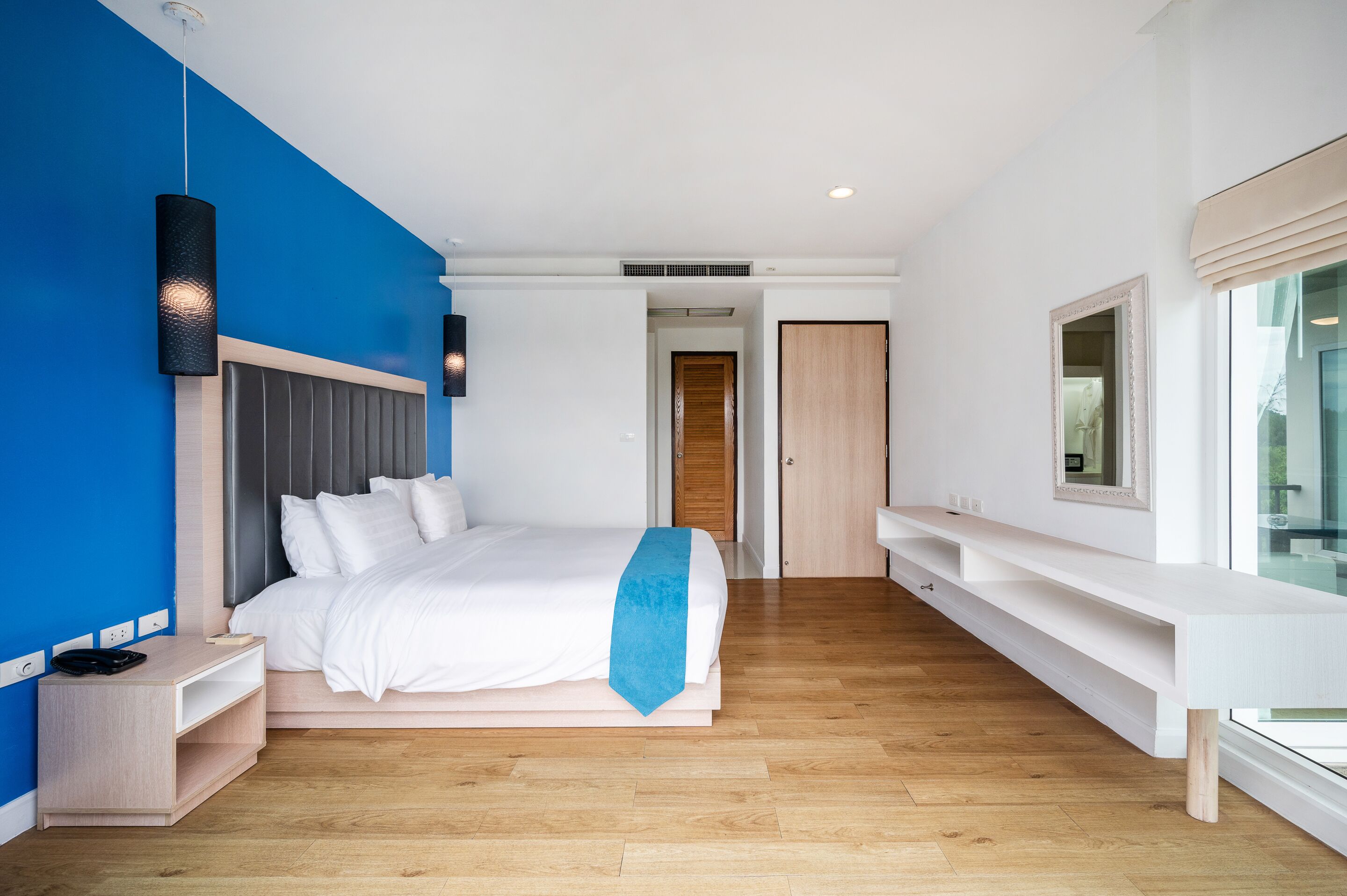 A modern bedroom with a bed, bedside table, and a large window.