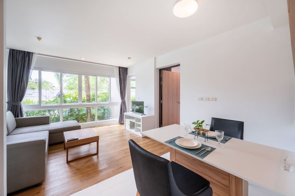 Una sala de estar moderna con un sofá, una mesa de centro y un comedor con una mesa preparada para dos.