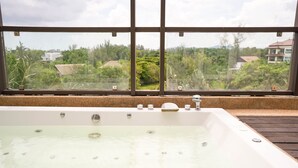 Una bañera amplia con vistas a una zona residencial a través de una ventana.