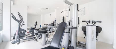 A gym with various exercise equipment, including a bench, weight machines, and cardio machines.