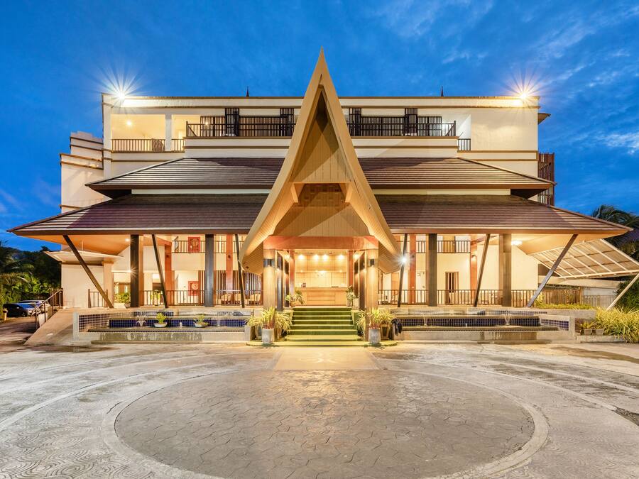 Un hotel moderno con una entrada triangular destacada, varios balcones y una fachada bien iluminada.