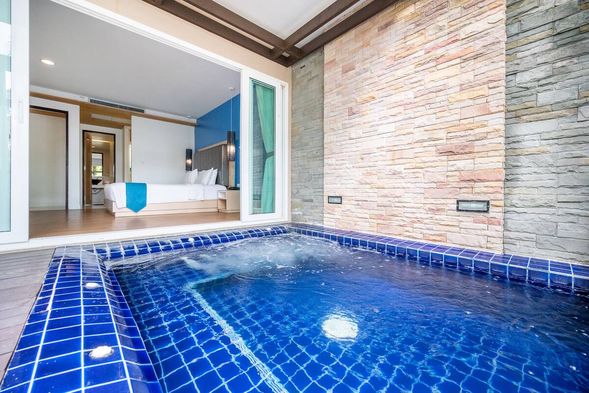Una habitación de hotel con un ventanal grande, una cama y un baño visible a través de la puerta.