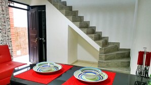 Una sala moderna con una escalera, un sofá rojo y dos cuencos sobre individuales rojos.