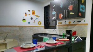 Una cocina con encimera negra, un fregadero y una estufa. Hay platos, tazas y utensilios sobre la encimera.