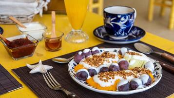 Un desayuno con un plato de comida, una taza de café y un vaso de jugo de naranja sobre una mesa amarilla.