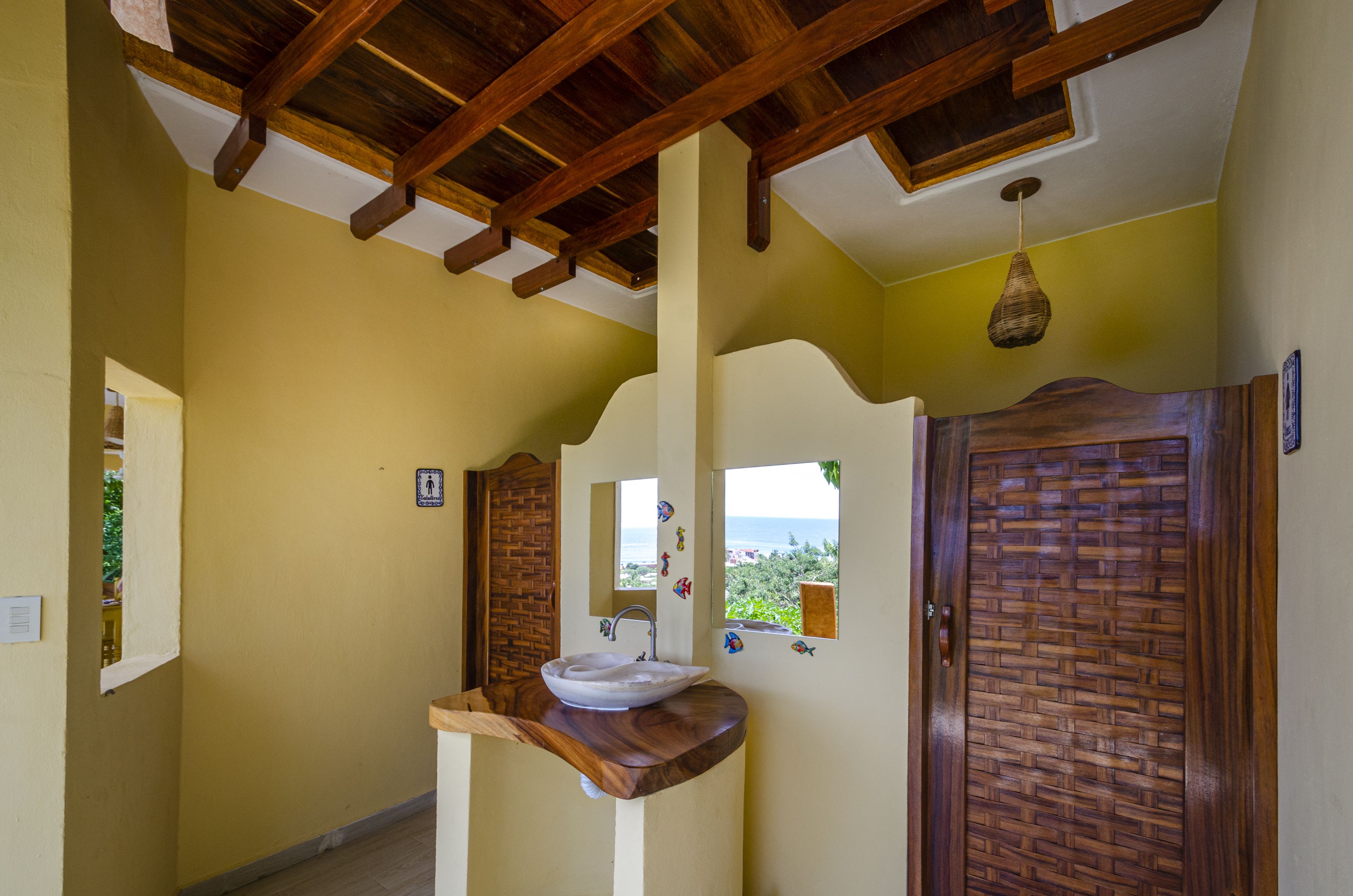 Un baño con tocador de madera, lavamanos y vista al exterior a través de una ventana.
