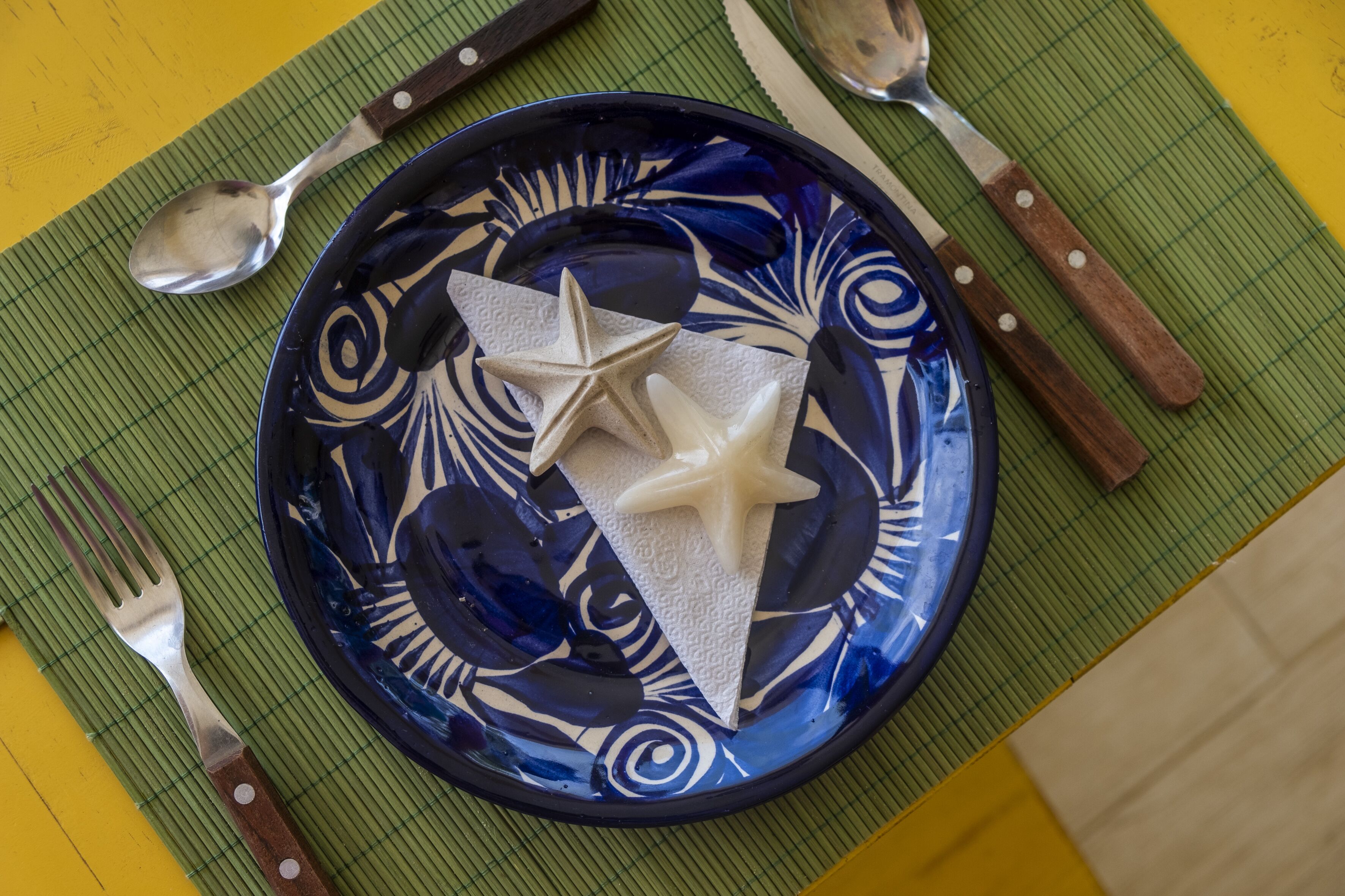 Un plato azul con una estrella y una servilleta sobre un mantel individual verde.