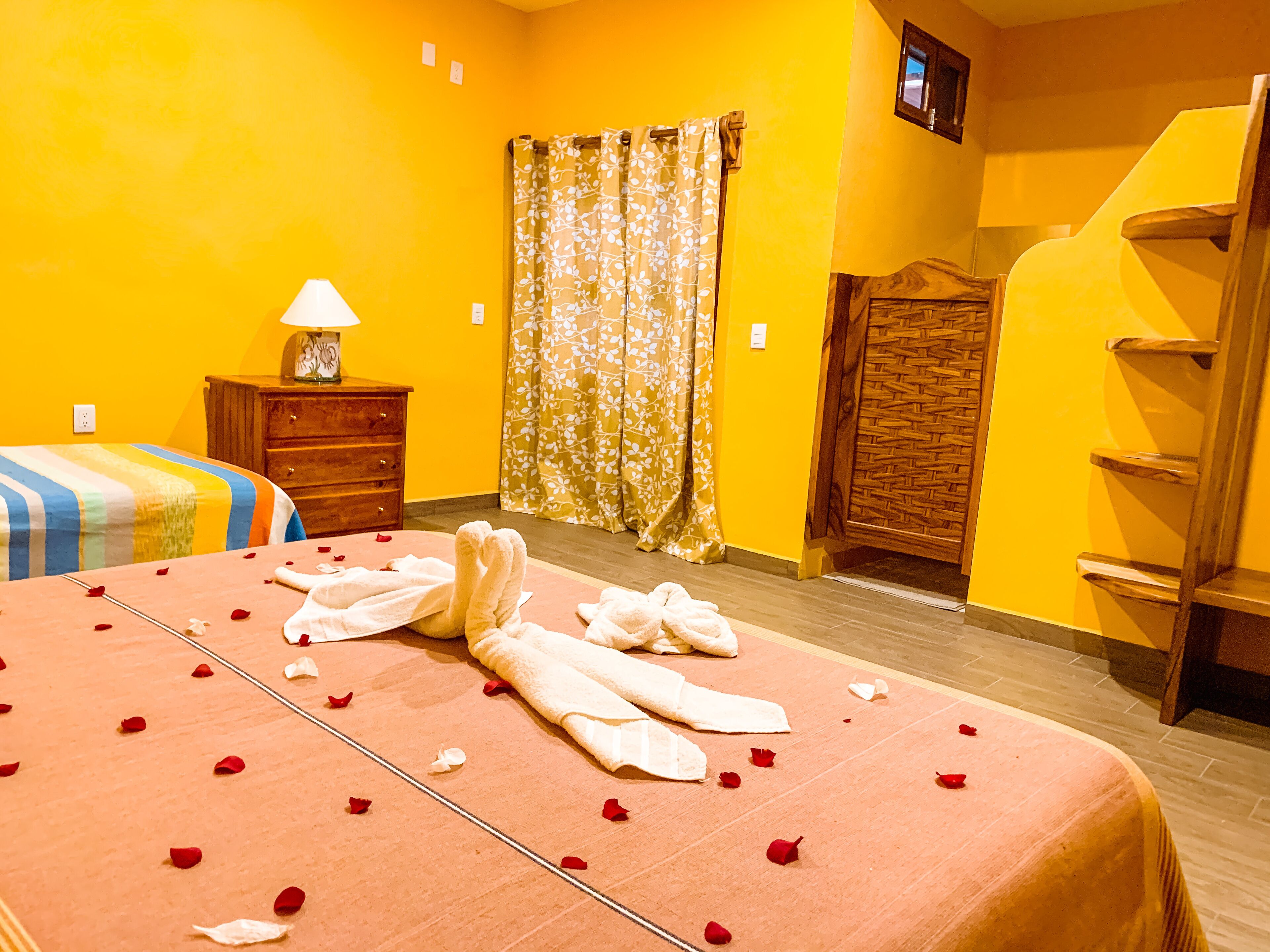Habitación de hotel con cama, mesita de noche, lámpara, armario de madera y zona de ducha.