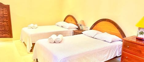Ein Hotelzimmer mit zwei Einzelbetten, einer Holzkommode und einer Wand-Klimaanlage.