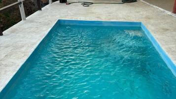 Una piscina rectangular con agua azul cristalina, rodeada por una plataforma de hormigón.
