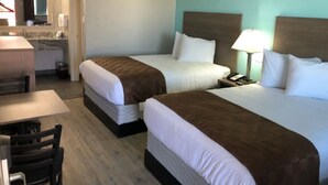 Habitació d'hotel amb dos llits, un escriptori i un bany.