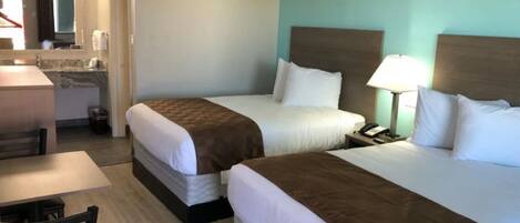 Habitación de hotel con dos camas, un escritorio y un baño.