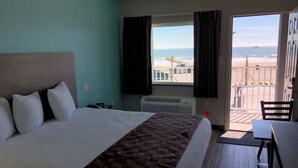 Una habitació d'hotel amb un llit, una taula de treball i vista a la platja.