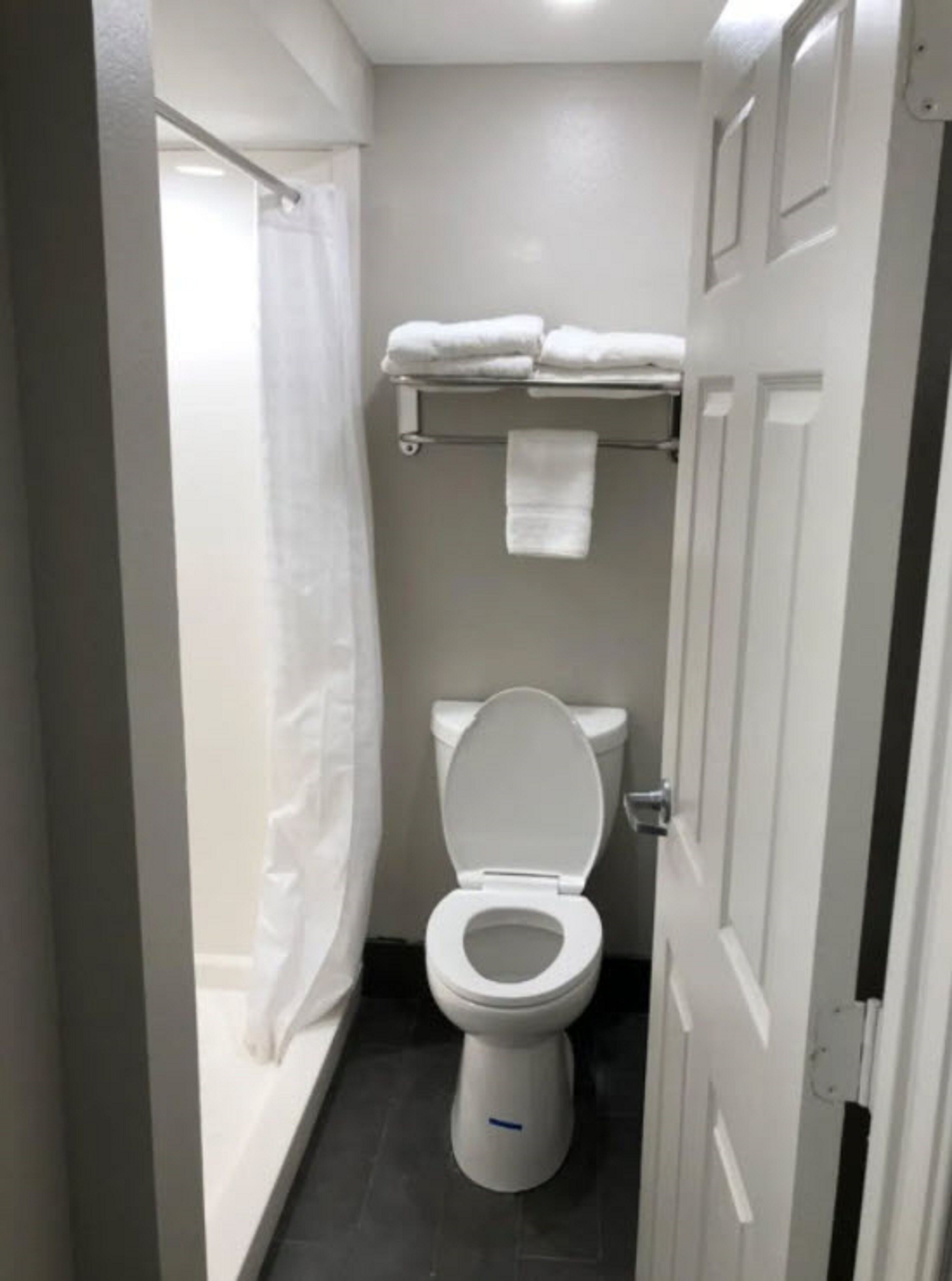 A small, clean bathroom with a toilet, a shower curtain, and a towel rack with folded towels.