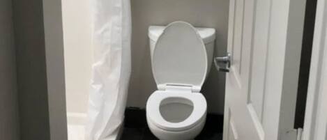 A small, clean bathroom with a toilet, a shower curtain, and a towel rack with folded towels.